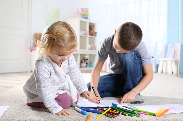 Two cute little children sitting on floor and painting