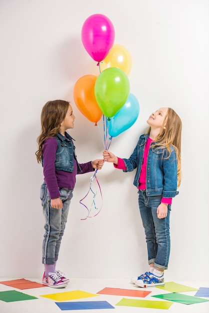 Two cute little girls with colorful balloons