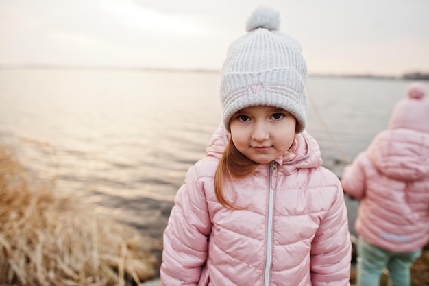 Two cute sisters on the shore of the lake