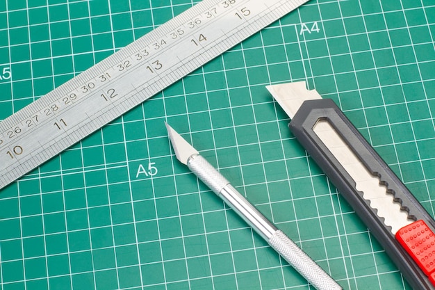 Two cutters and a metal ruler on a green cutting mat