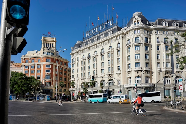 Two cyclists passing in front of the famous and luxurious Palace hotel in Madrid