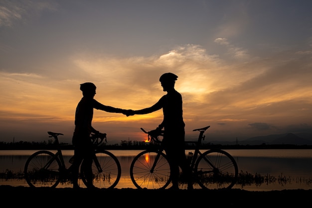 Two cyclists shaking hand after finish ride bicycle together. sportsmanship concept.