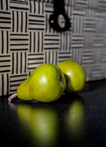 Two decoration pears on a black table in front of a decoration stripped box