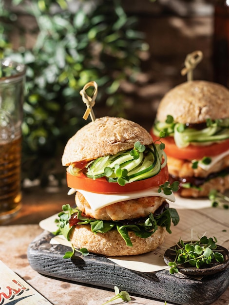 Two delicious homemade burgers of beef cheese and vegetables on wooden board at greenery background