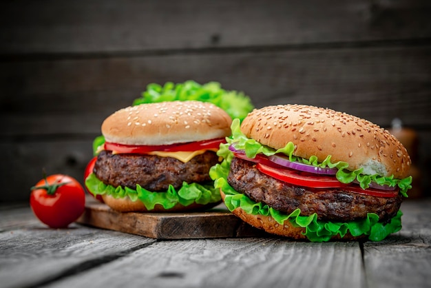 Two delicious homemade burgers of beef on an old wooden table Fat unhealthy food closeup