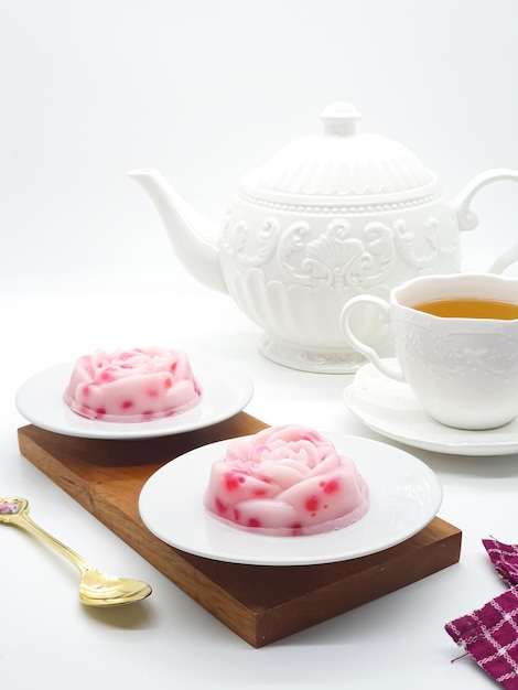 Two desserts on plates with a tea pot in the background.