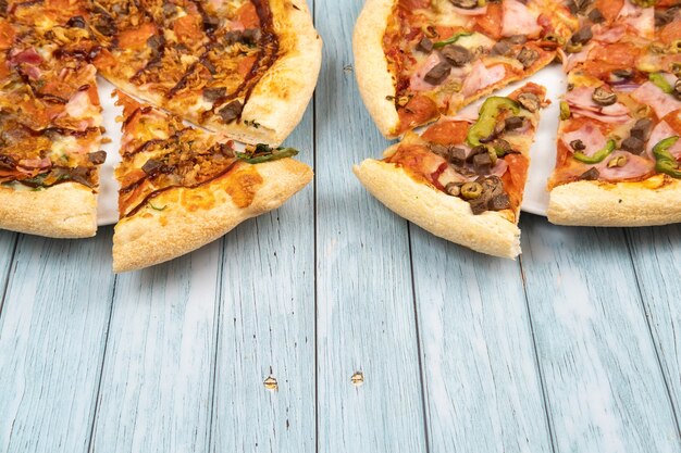 Two different delicious big pizzas on a blue wooden background