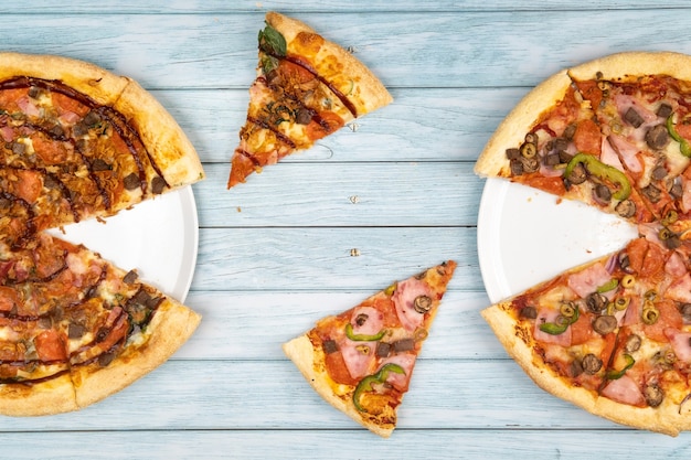 Two different delicious big pizzas on a blue wooden background