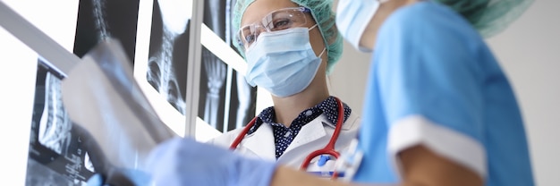 Two doctor in suits, medical gloves and protective masks hold X-ray photograph.