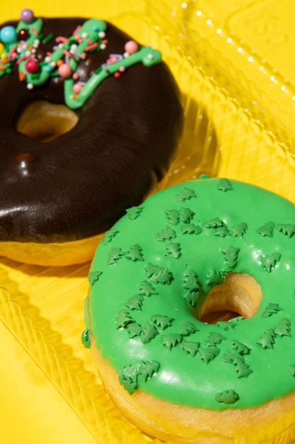 Two donuts chocolate and green on a yellow background in a box closeup Studio vertical photo