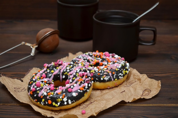 Two donuts and cups with coffee on a wooden background