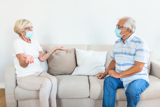 Two Elderly friends sitting in social distance wearing protective mask