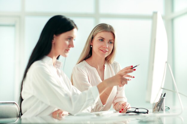 Two employees are discussing something sitting at the office table