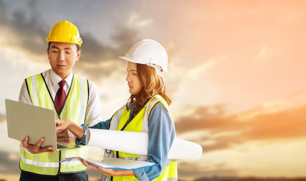 Two engineer male and female is discussing on document plant with senset sky in the background.