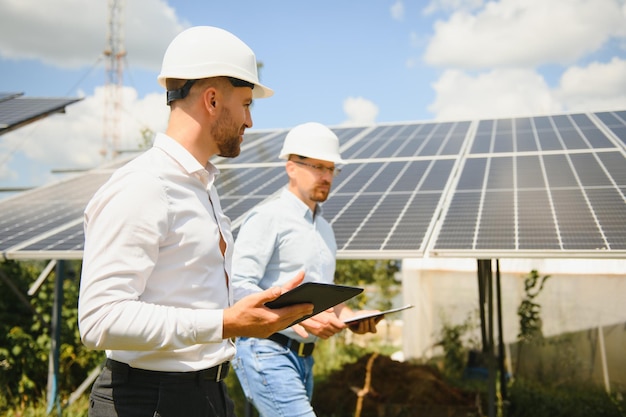 Two engineers are conducting outdoor inspection of solar photovoltaic panels