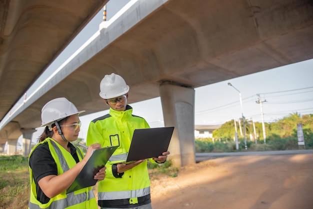 Two engineers discuss about work at the site of large bridge under constructionManagement consulting people discussion with engineers about the progress and construction planning of highway