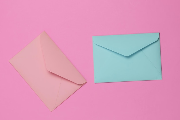 Two envelopes of pink and blue pastel colors on pink background Flat lay mockup for valentines day wedding or birthday