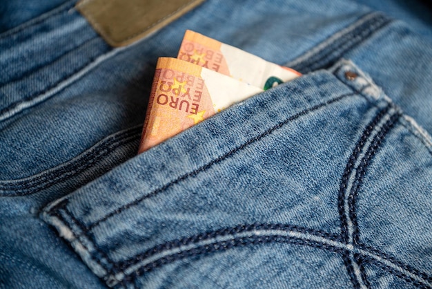 Two euro banknotes peek out from back pocket of old blue jeans