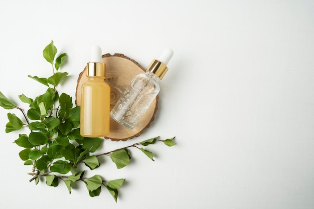 Two face serum or essential oil dropper bottles lying on a wooden plate in a cosmetology salon