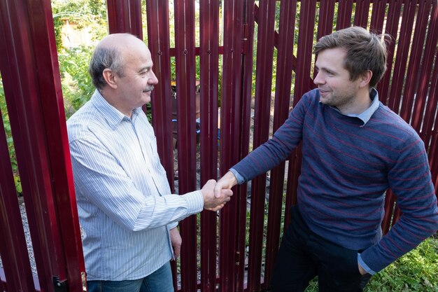 Photo two farmers neighbours shaking hands and takling to each other on sunny day