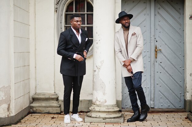 Two fashion black men. Fashionable portrait of african american male models. Wear suit, coat and hat.