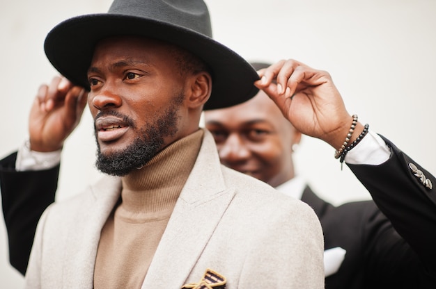 Two fashion black men. Fashionable portrait of african american male models. Wear suit, coat and hat.