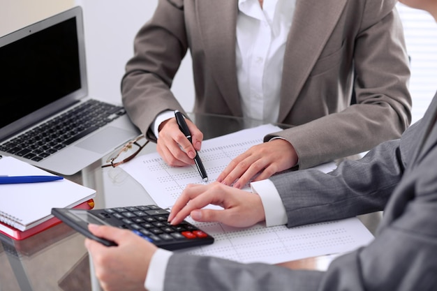 Two female accountants counting on calculator income for tax form completion hands closeup. Internal Revenue Service inspector checking financial document. Planning budget, audit  concept