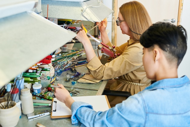 Two Female Artists Collaborating in Glassworking Shop