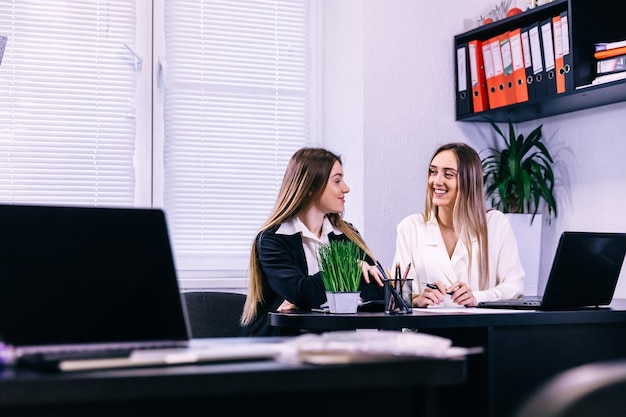 Two female colleagues in office working together with smile on f