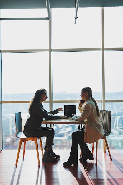 Two female coworkers and colleagues discussing working together on business project using laptop female executive explaining new online idea to coworker analyzing compute