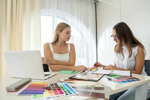 Two female designers working with house paln and color palette interior design