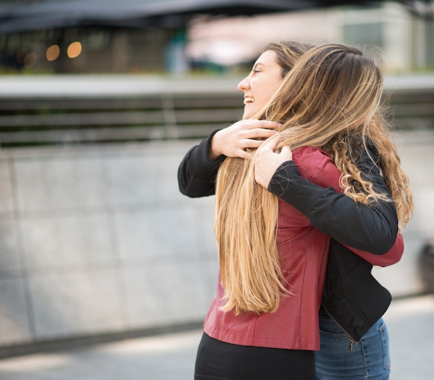 Two female friends hugging outdoor