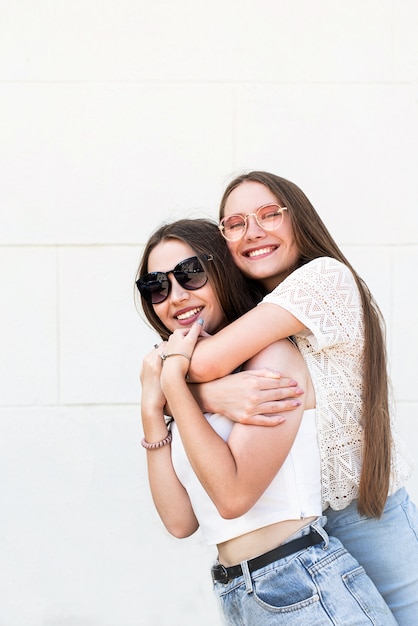 Two female friends hugging outside in a summer day having fun