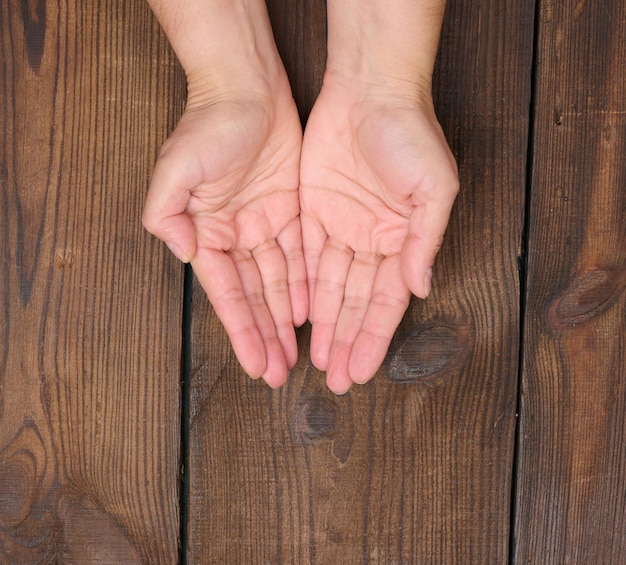 Two female hands on a brown background Empty palms open top view