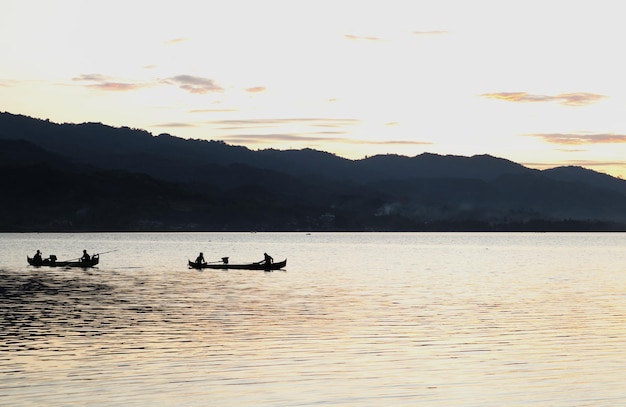 two fishermen on the lake from a boat at sunset. Limboto Lake, Gorontalo, Indonesia. beautiful sky i