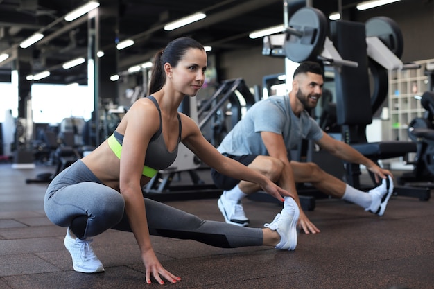 Two fit people doing stretching exersices in crossfit gym.