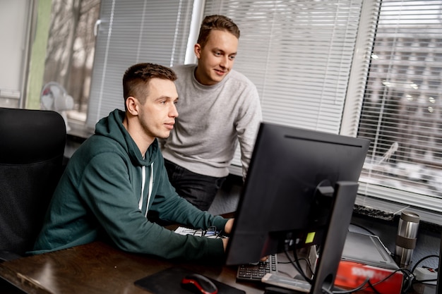 Two focused employees sit together at a table in a modern office