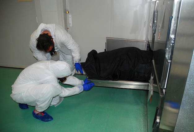 Two forensic workers take the body of a person out of a cold room