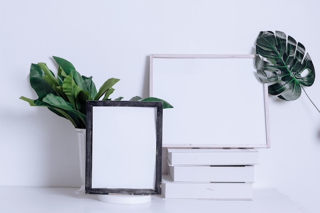 Two frames mockup with decor elements, flowers and books over the white wall.