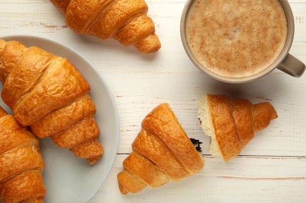 Two french croissants on plate and cup of coffee on white background