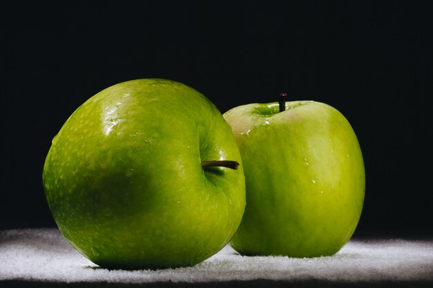 Two fresh green apples on a dark background