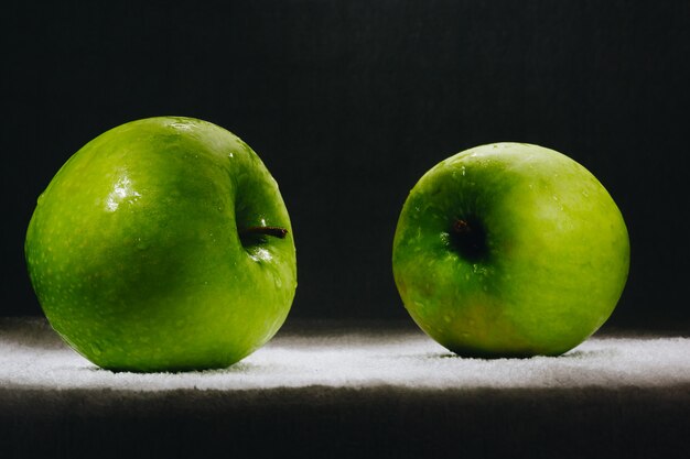 Two fresh green apples on a dark background