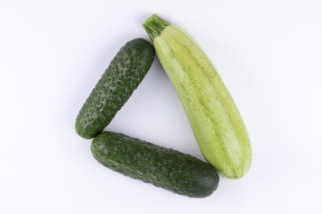 Two fresh green cucumbers and zucchini isolated on white background Closeup of green vegetables Healthy food concept