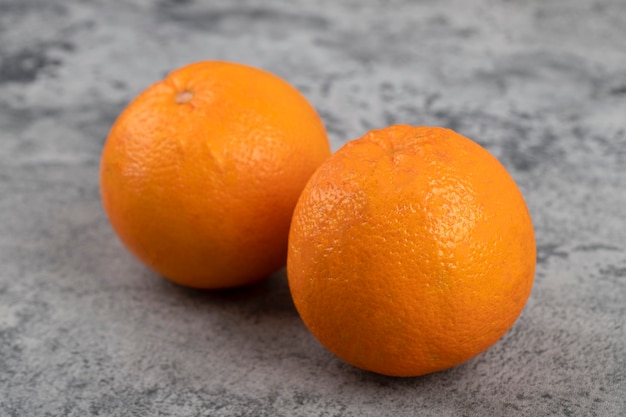 Two fresh healthy oranges isolated on a stone table.