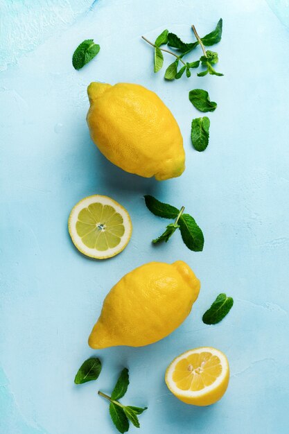 Two fresh lemons in blue plate on turquoise concrete background. Food background. Top view.