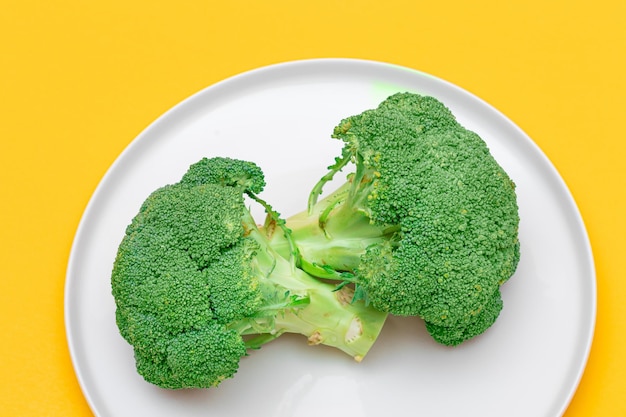 Two fresh and raw pieces of broccoli on white plate uncooked green cabbage