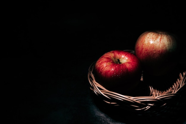 two fresh red apple with water droplets on a black background with space for text.