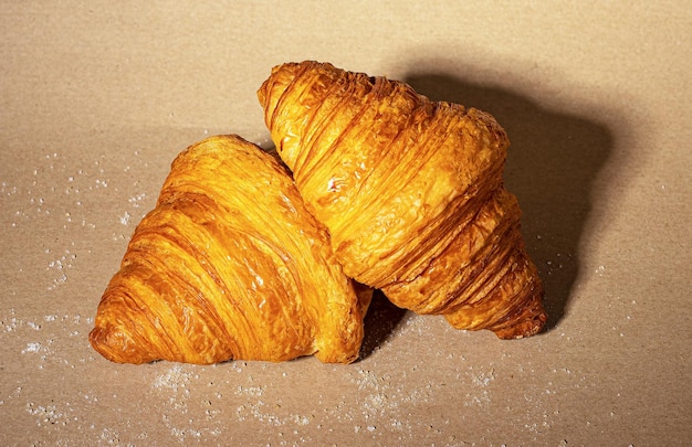 Two fresh twisted croissants on kraft paper background French bakery composition