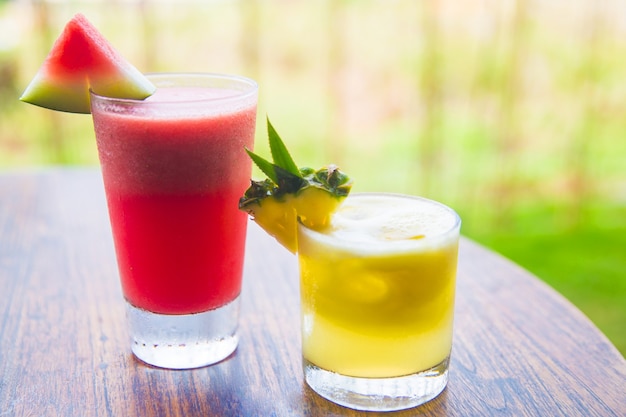 Two fresh watermelon and pineapple juices on the wooden desk. Selective focus. Vacation concept.