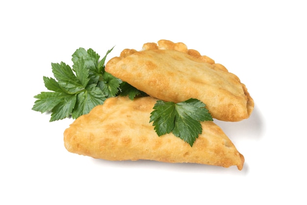 Two fried chebureks and parsley leaves isolated on a white background